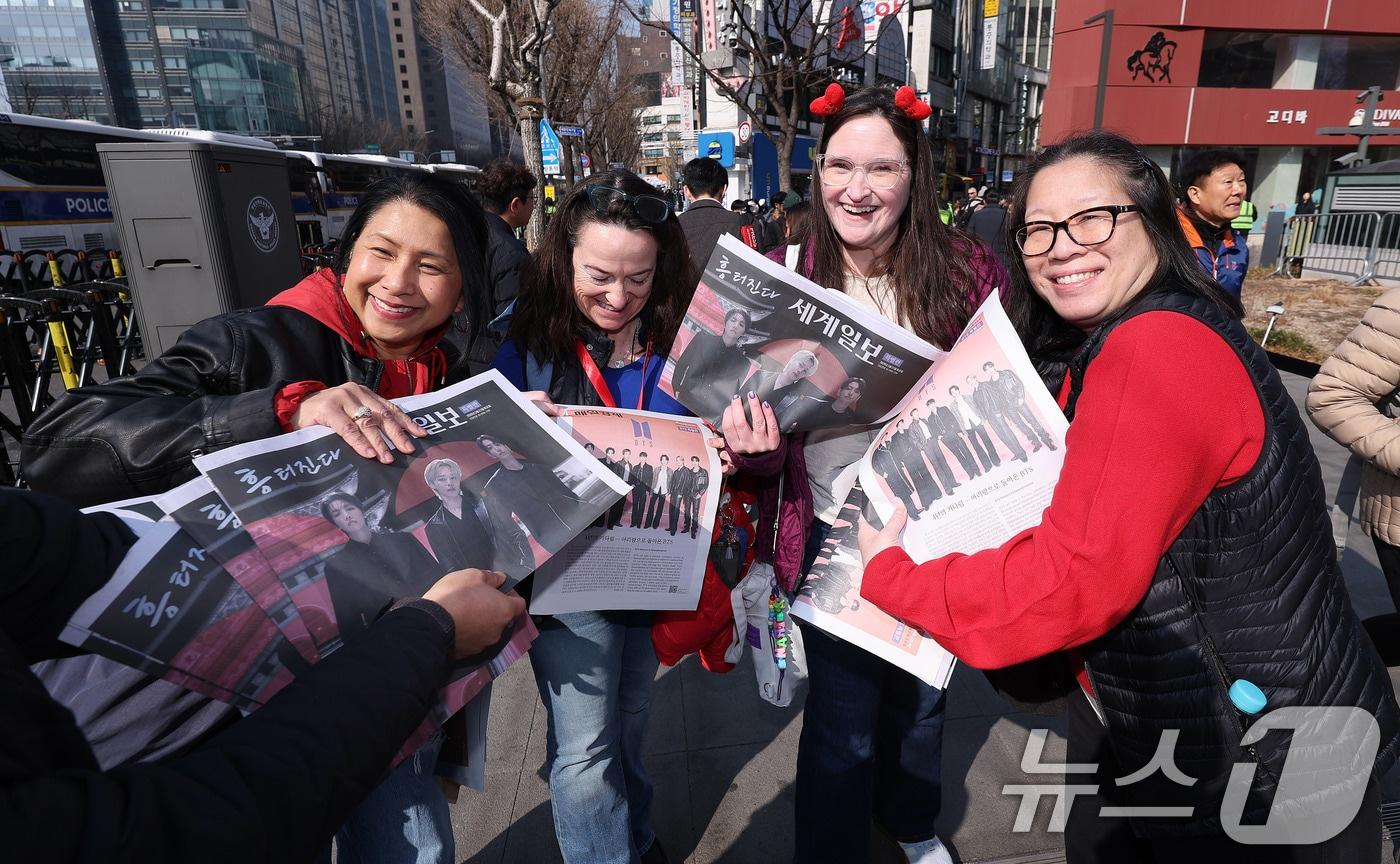 본문 이미지 - 방탄소년단(BTS) 컴백 공연일인 21일 오전 서울 광화문광장 인근에서 외국인 관광객들이 일간지들이 배포한 BTS 관련 특별판을 들고 있다. 2026.3.21 ⓒ 뉴스1 박지혜 기자