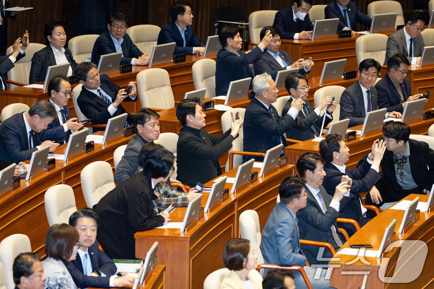 본문 이미지 - 더불어민주당 의원들이 21일 서울 여의도 국회에서 열린 제433회 국회(임시회) 제2차 본회의에서 중대범죄수사청 조직 및 운영에 관한 법률안(대안)이 가결되는 모습을 휴대전화로 촬영하고 있다. ⓒ 뉴스1 유승관 기자