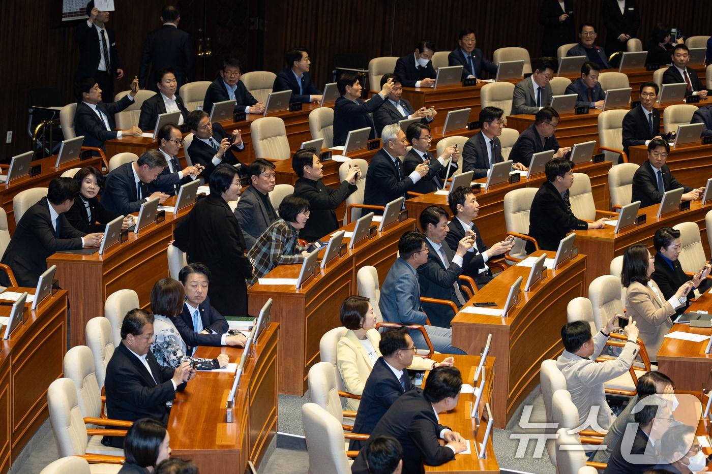 본문 이미지 - 더불어민주당 의원들이 21일 서울 여의도 국회에서 열린 제433회 국회(임시회) 제2차 본회의에서 중대범죄수사청 조직 및 운영에 관한 법률안(대안)이 가결되는 모습을 휴대전화로 촬영하고 있다. 2026.3.21 ⓒ 뉴스1 유승관 기자