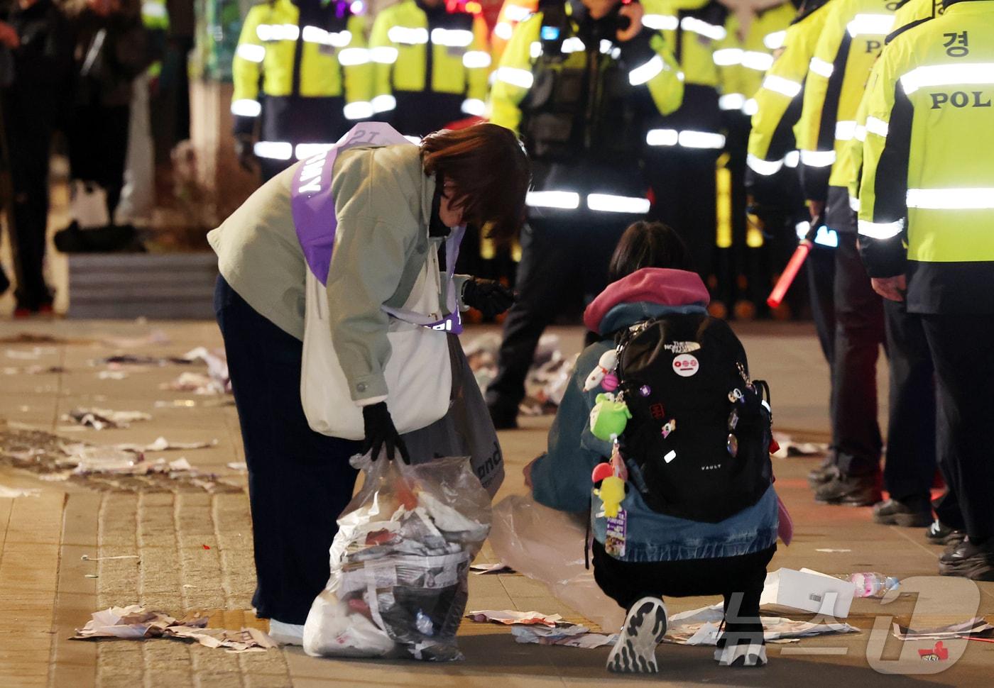 본문 이미지 - 21일 오후 서울 종로구 광화문광장에서 열린 'BTS 컴백 라이브: 아리랑'이 끝난 후 한 아미 자원봉사단원이 쓰레기를 치우고 있다. 2026.3.21 ⓒ 뉴스1 김진환 기자