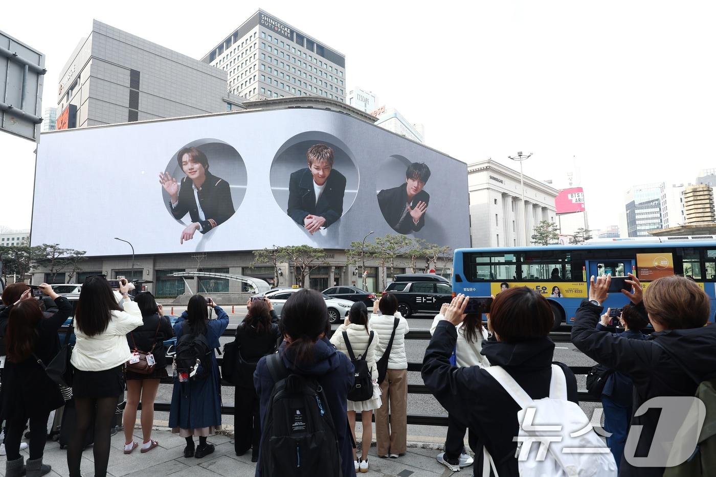 본문 이미지 - 방탄소년단(BTS) 컴백 공연 다음 날인 22일 오전 서울 중구 신세계백화점 인근에서 방탄소년단의 팬클럽 ARMY가 송출되는 BTS의 모습을 사진 찍고 있다. 2026.3.22 ⓒ 뉴스1 김민지 기자