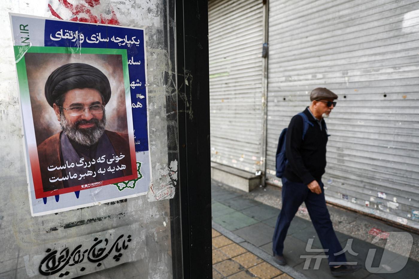 본문 이미지 - 22일 이란 수도 테헤란의 한 거리에 새 최고지도자인 모즈타바 하메네이의 포스터가 붙어 있다. 2026.3.22 ⓒ 로이터=뉴스1