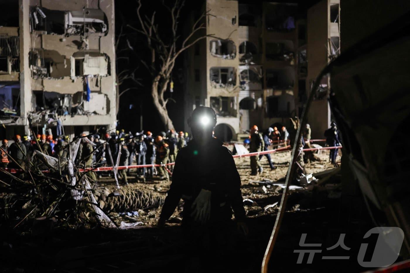 본문 이미지 - 22일(현지시간) 새벽 이스라엘 구조대가 전날 이란 미사일 공격을 받은 아라드의 건물들을 점검하고 있다.2026.03.22. ⓒ AFP=뉴스1