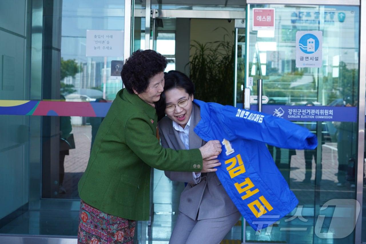 본문 이미지 - 22일 제9회 전국동시지방선거 더불어민주당 강진군수 예비후보로 등록한 김보미 전남 강진군의원(36·여)에게 한 지지자가 민주당 점퍼를 입혀주고 있다.(김보미 제공, 재배포 및 DB 금지)2026.3.23 ⓒ 뉴스1