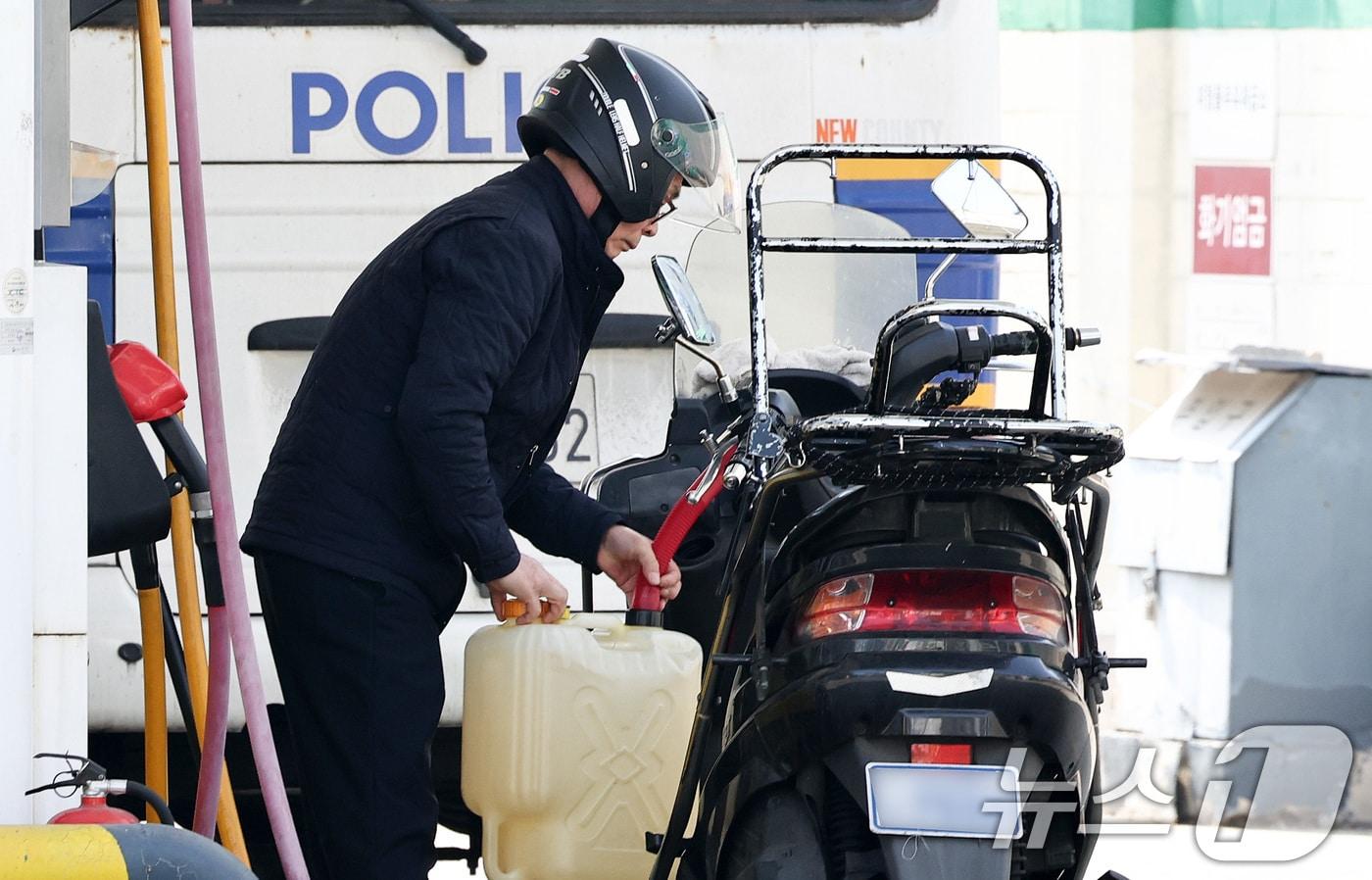 본문 이미지 - 이란 전쟁 여파로 고유가가 지속되고 있는 23일 서울의 한 주유소에서 한 운전자가 주유를 마친 기름통을 오토바이에 싣고 있다. 2026.3.23 ⓒ 뉴스1 최지환 기자