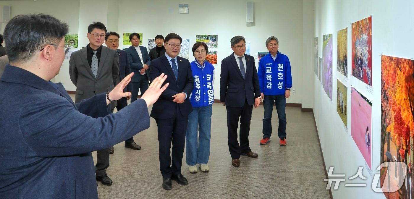 본문 이미지 - 김얼(왼쪽) 전북사진기자협회 협회장이 23일 전북 전주시 전북대학교 JBNU컨벤션센터 전시실에서 열린 '2026 전북보도사진전'에서 내빈들과 함께 전시 라운딩을 하고 있다.(전북사진기자협회 제공. 재판매 및 DB금지)