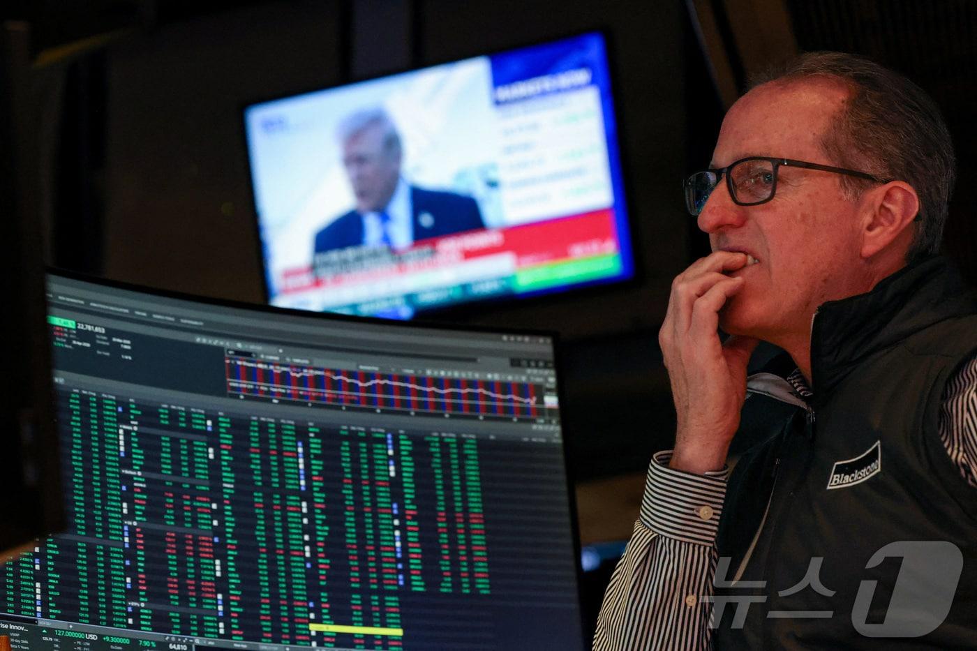 본문 이미지 - 뉴욕증권거래소에서 한 트레이더가 23일(현지시간) 도널드 트럼프 대통령이 나오는 뉴스 스크린 앞에서 근무하고 있다. 2026.3.23ⓒ 로이터=뉴스1