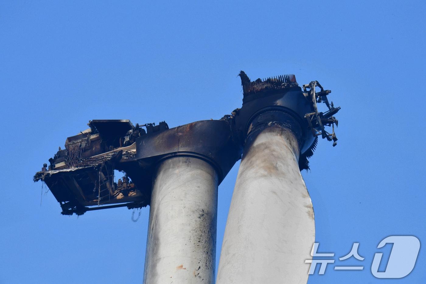 본문 이미지 - 경북 영덕군 창포리 풍력발전기 화재 이틀째인 24일 오전 소방당국이 발전기 블레이드에 남은 불을 진화하고 있다. 불로 새까맣게 탄 발전기 모습.2026.3.24 ⓒ 뉴스1 최창호 기자