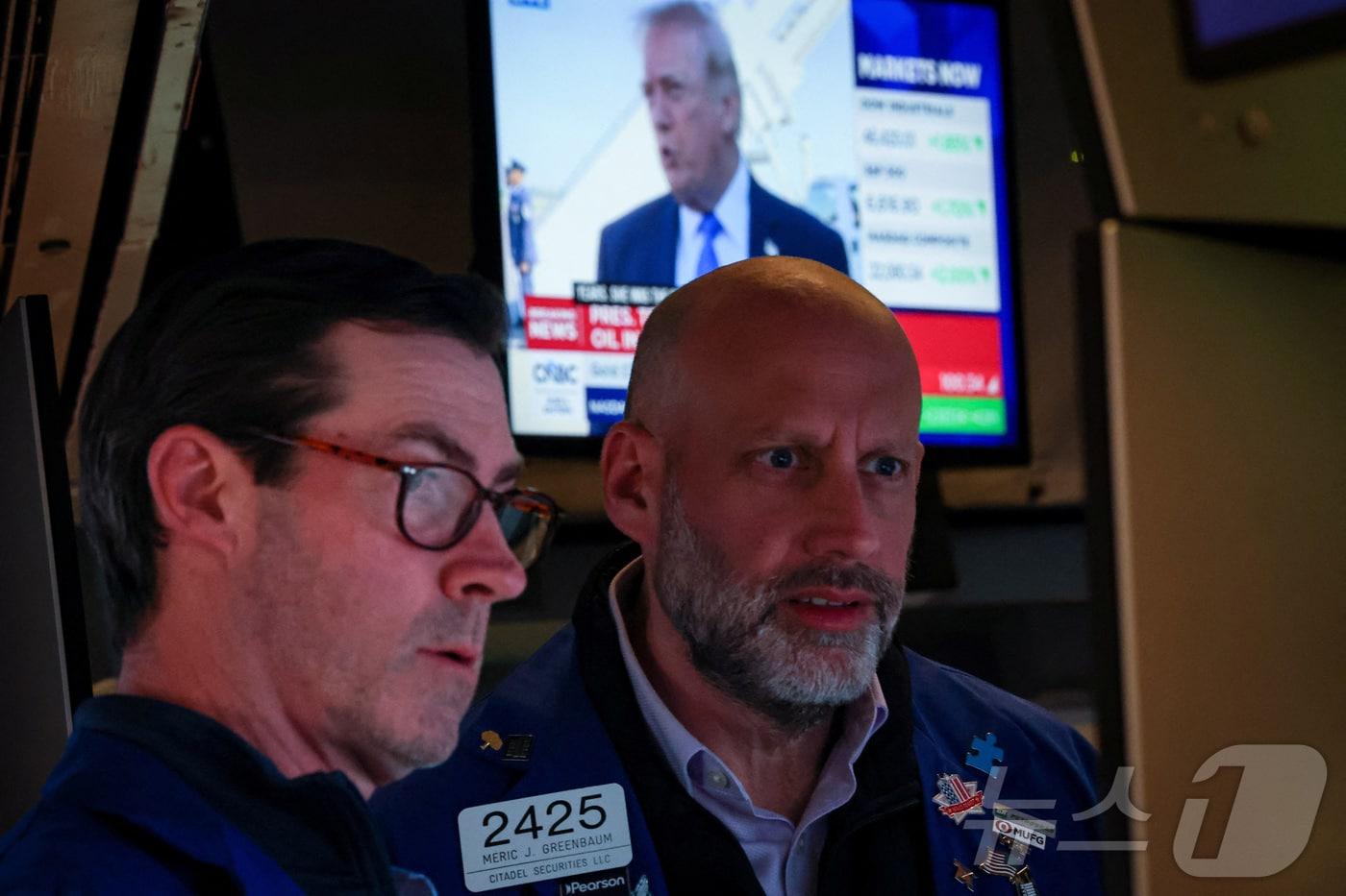 본문 이미지 - 23일(현지시간) 도널드 트럼프 미국 대통령이 발언하는 뉴스 방송이 나오는 스크린을 뒤로 하고 뉴욕증권거래소(NYSE) 트레이더들이 근무하고 있다. 2026.3.23 ⓒ 로이터=뉴스1