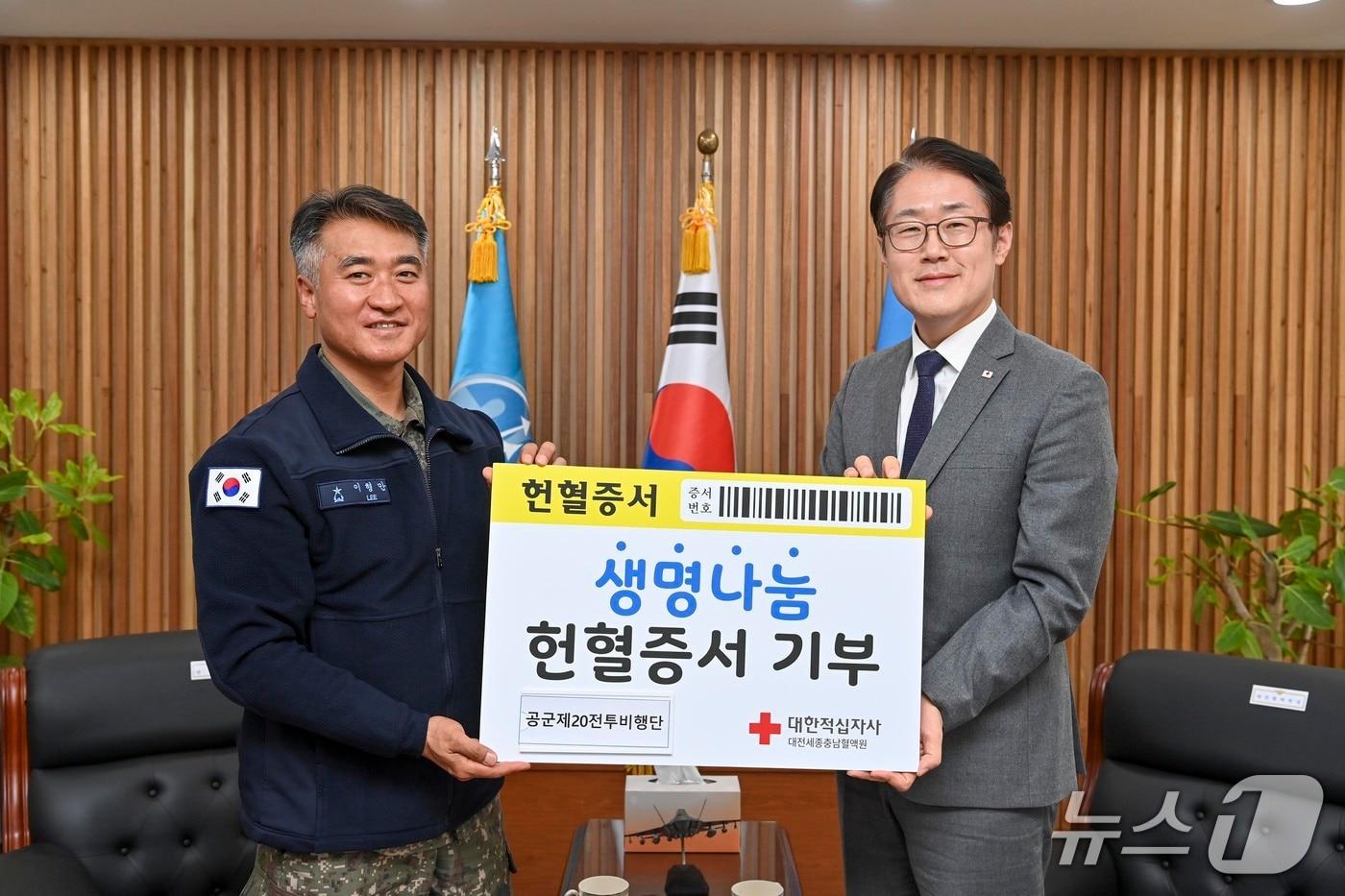 본문 이미지 - 공군 제20전투비행단장 이형만 준장(왼쪽)과 성낙준 대한적십자사 대전세종충남혈액원장이 헌혈 기부증서 기념판을 들고 기념촬영을 하고 있다.(이재민 중사 제공. 재판매 및 DB금지)2026.3.24/뉴스1