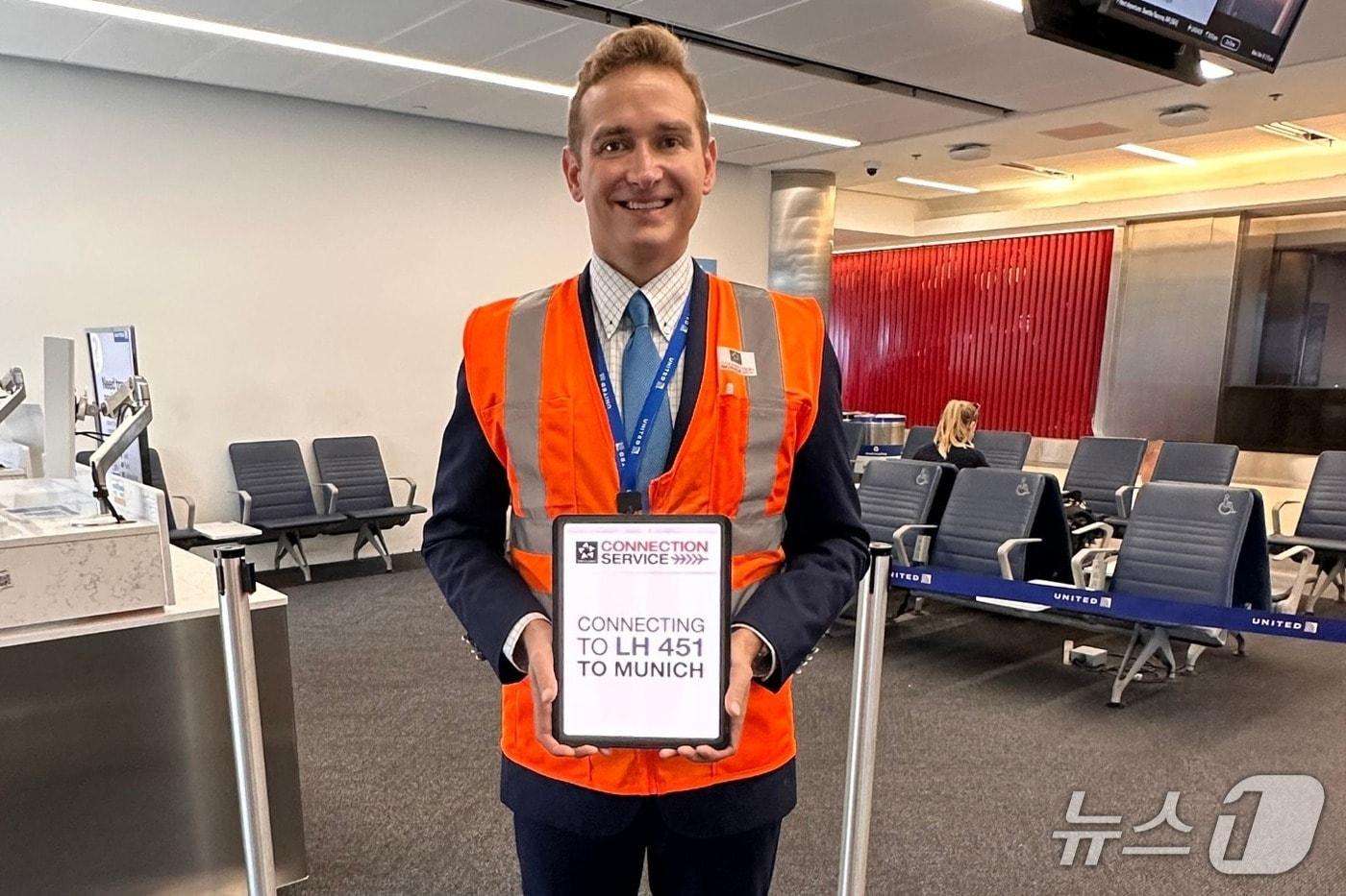 본문 이미지 - 23일(현지시각) 미국 로스앤젤레스(LA) 국제공항에 문을 연 스타얼라이언스 환승 지원 센터인 '스타 커넥션 센터'에서 직원이 승객을 대상으로 한 환승 안내 팻말을 들고 있는 모습(자료사진. 아시아나항공 제공). 2026.3.23.