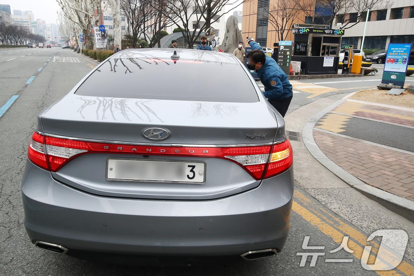 본문 이미지 - 공공부문 승용차 5부제(요일제) 의무 시행 첫날인 25일 오전 대구 수성구청 입구에서 구청 청원경찰이 부제 대상 차량(수요일·차량 끝자리 3, 8번) 운전자에게 인근 주차장 이용을 안내하고 있다. 2026.3.25 ⓒ 뉴스1 공정식 기자