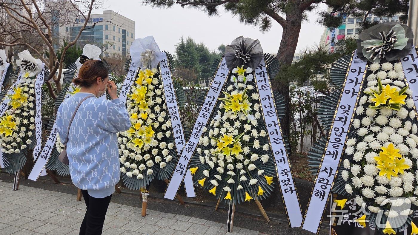 본문 이미지 - 25일 대구지법 앞에 아동학대살해 등의 혐의로 기소된 30대 친부 A씨에 대한 엄벌을 촉구하는 근조 화환이 놓여 있다. 한 시민이 눈물을 흘리고 있다.2026.3.25 ⓒ 뉴스1 이성덕 기자