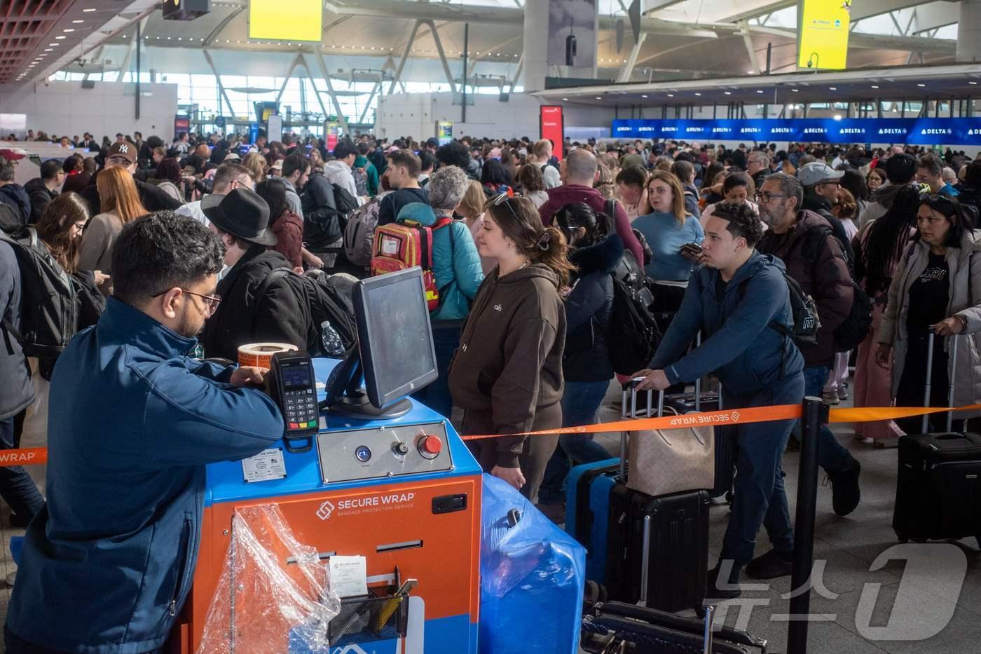 본문 이미지 - 25일(현지시간) 뉴욕 JFK국제공항을 이용하려는 탑승객들이 보안검색을 받기 위해 길게 줄을 서 있다. 미국 국토안보부(DHS) 부분 셧다운(일시적 업무 중단)이 6주째 이어지며 무급 근무에 버티지 못한 교통안전청(TSA) 직원이 500명 가까이 사직하고 3100명 이상이 결근해 '공항 대란'이 심화되고 있다. 이로 인해 교통안전청(TSA) 역사상 가장 긴 대기 시간이 발생했으며, 일부 공항에선 4시간 반이 넘게 대기하고 있다. 도널드 트럼프 대통령은 공항 업무 지원을 위해 주방위군 투입을 검토하고 있다. ⓒ AFP=뉴스1
