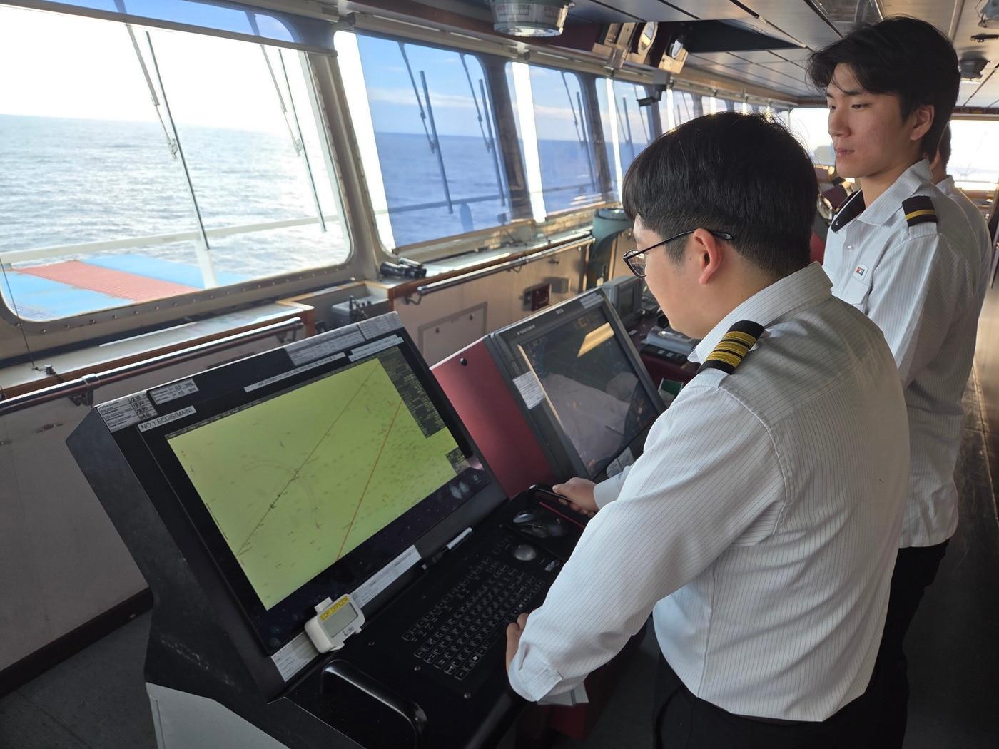 본문 이미지 - SM상선의 4253TEU급 컨테이너선 에스엠 뭄바이(SM MUMBAI)호의 항해사들이 안전한 운항과 항로상의 위험요소 점검을 위해 브릿지(선교)에서 실시간 기상정보를 확인하고 있다. (SM그룹 제공)