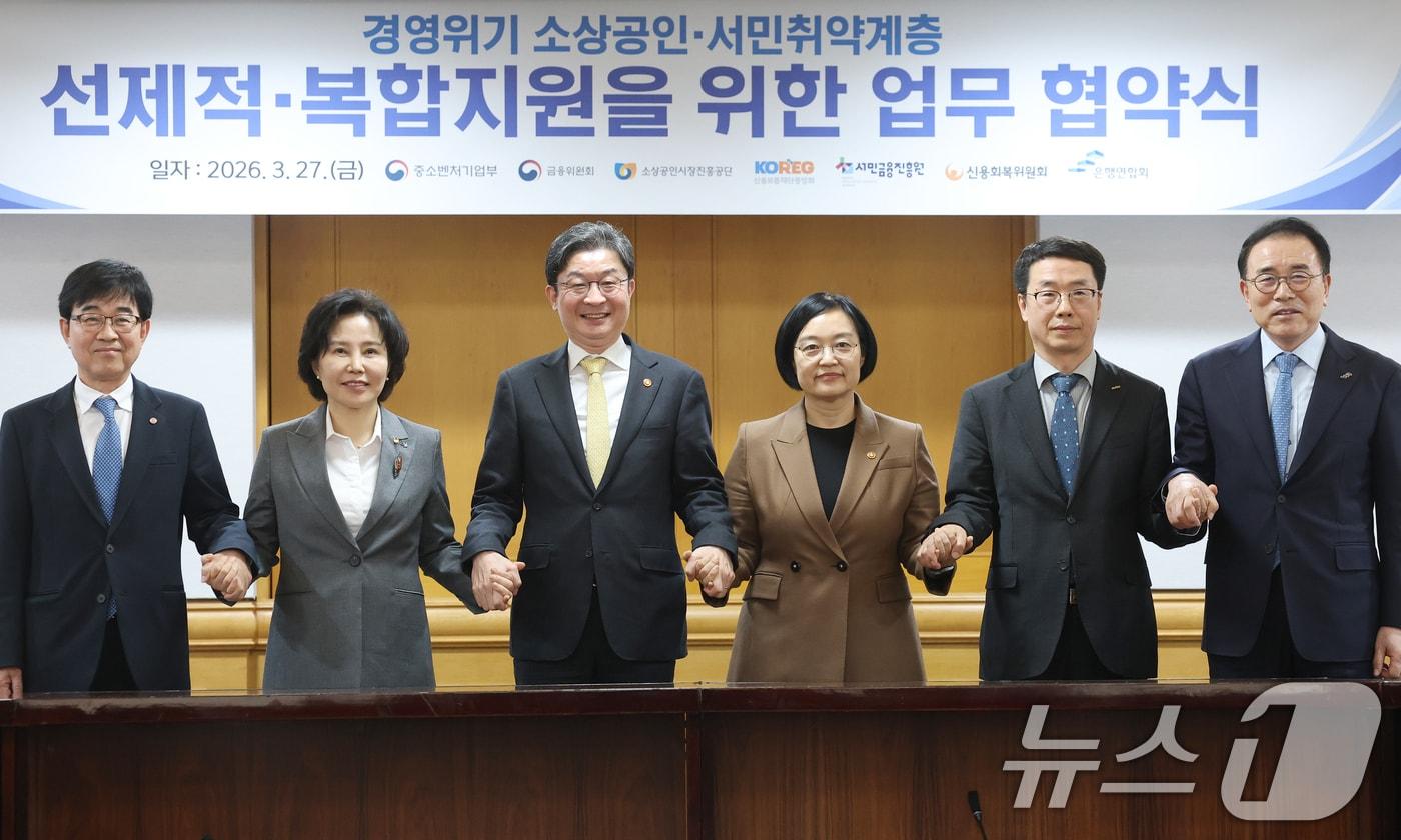 본문 이미지 - 한성숙 중소벤처기업부 장관과 이억원 금융위원장이 지난3월 27일 서울 중구 은행회관에서 열린 경영위기 소상공인·서민취약계층 선제적·복합지원을 위한 업무 협약식에서 참석자들과 기념촬영을 하고 있다. 왼쪽부터 인태연 소상공인시장진흥공단 이사장, 김은경 서민금융진흥원장, 이 위원장, 한 장관, 원영준 신용보증재단중앙회장, 조용병 은행연합회장. 2026.3.27 ⓒ 뉴스1 오대일 기자