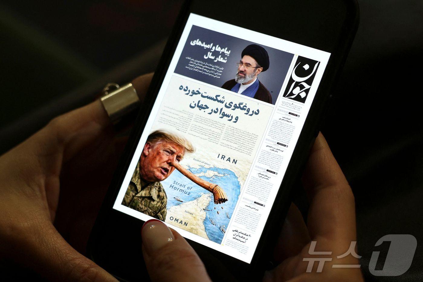 본문 이미지 - 한 이란 여성이 25일(현지시간) 테헤란에서 자바 신문의 디지털 사본을 휴대전화로 읽고 있다. 2026.3.25 ⓒ AFP=뉴스1