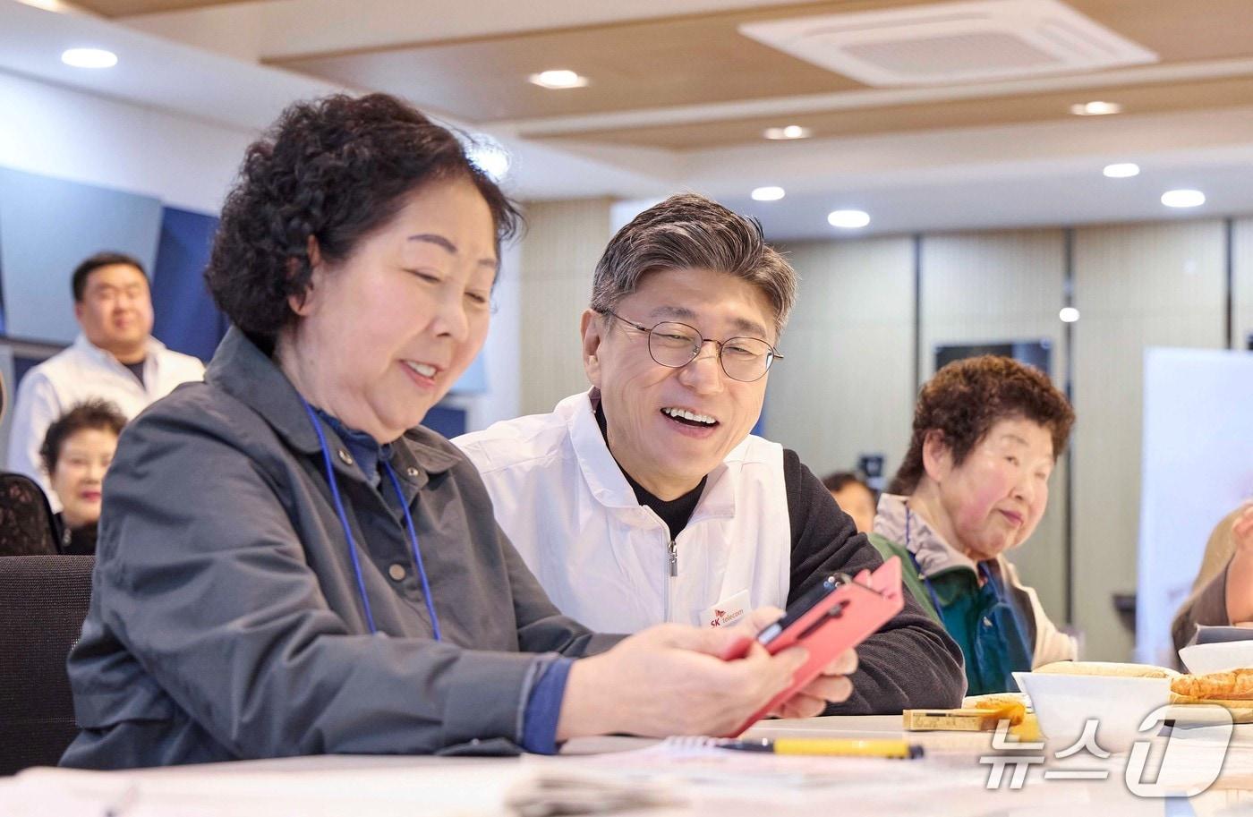 본문 이미지 - 정재헌 SKT CEO가 경기도 포천시 관인노인대학에서 어르신 고객의 스마트폰을 살펴보고 대화를 나누는 모습 (SKT 제공)