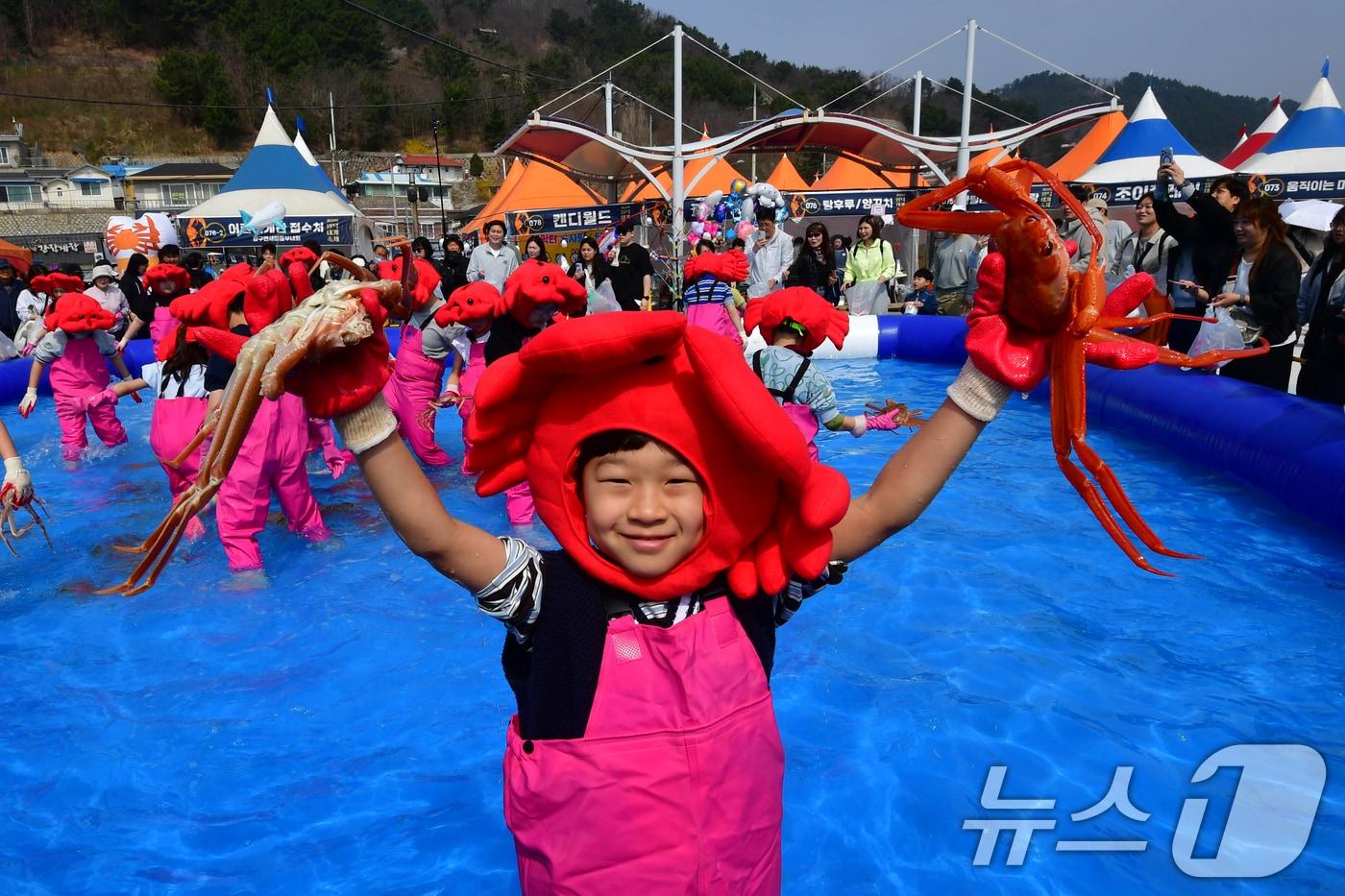 본문 이미지 - 제29회 경북 영덕 대게축제가 열린 강구항 해파랑공원에서 가족과 함께 온 어린이가 대게 맨손잡기 체험에서 잡은 대게를 번쩍 들고 있다. 2026.3.29 ⓒ 뉴스1 최창호 기자