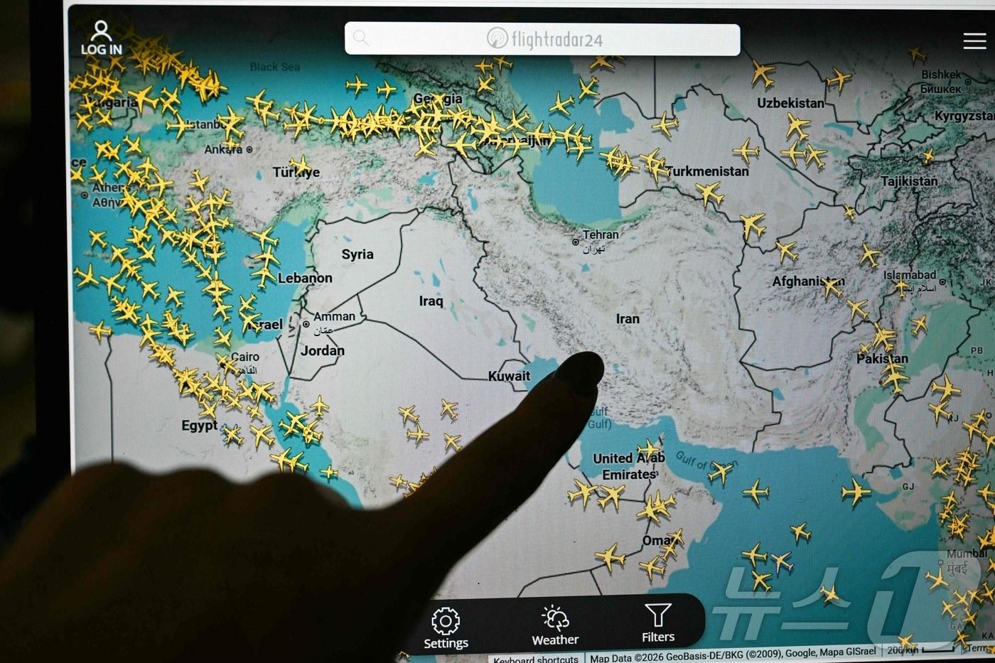 본문 이미지 - 한 사람이 1일(현지시간) 플라이트레이더24(Flightradar24) 화면을 가리키고 있다. 2026.3.1 ⓒ AFP=뉴스1