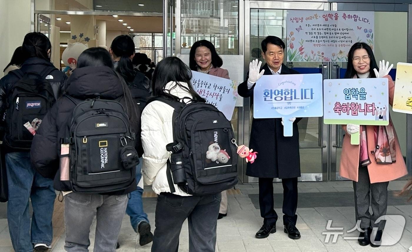 본문 이미지 - 심상웅 교육장(가운데)이 3일 신설 개교한 하남 한홀중학교에서 등교하는 학생들에게 환영인사를 하고 있다.(교육지원청 제공)
