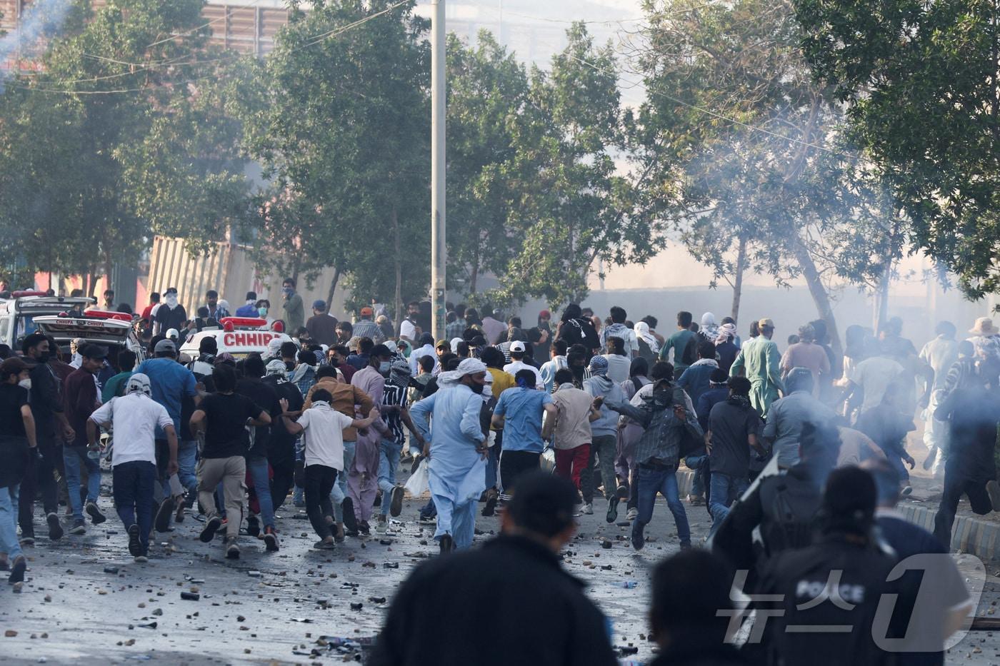 본문 이미지 - 1일(현지시간) 파키스탄 카라치에서 아야톨라 하메네이 이란 최고지도자 사망 소식이 전해진 뒤 이에 항의하는 시위가 일어난 가운데, 경찰이 군중을 해산하기 위해 최루탄을 발사하자 시위대가 흩어지고 있다. 2026.03.01. ⓒ 로이터=뉴스1