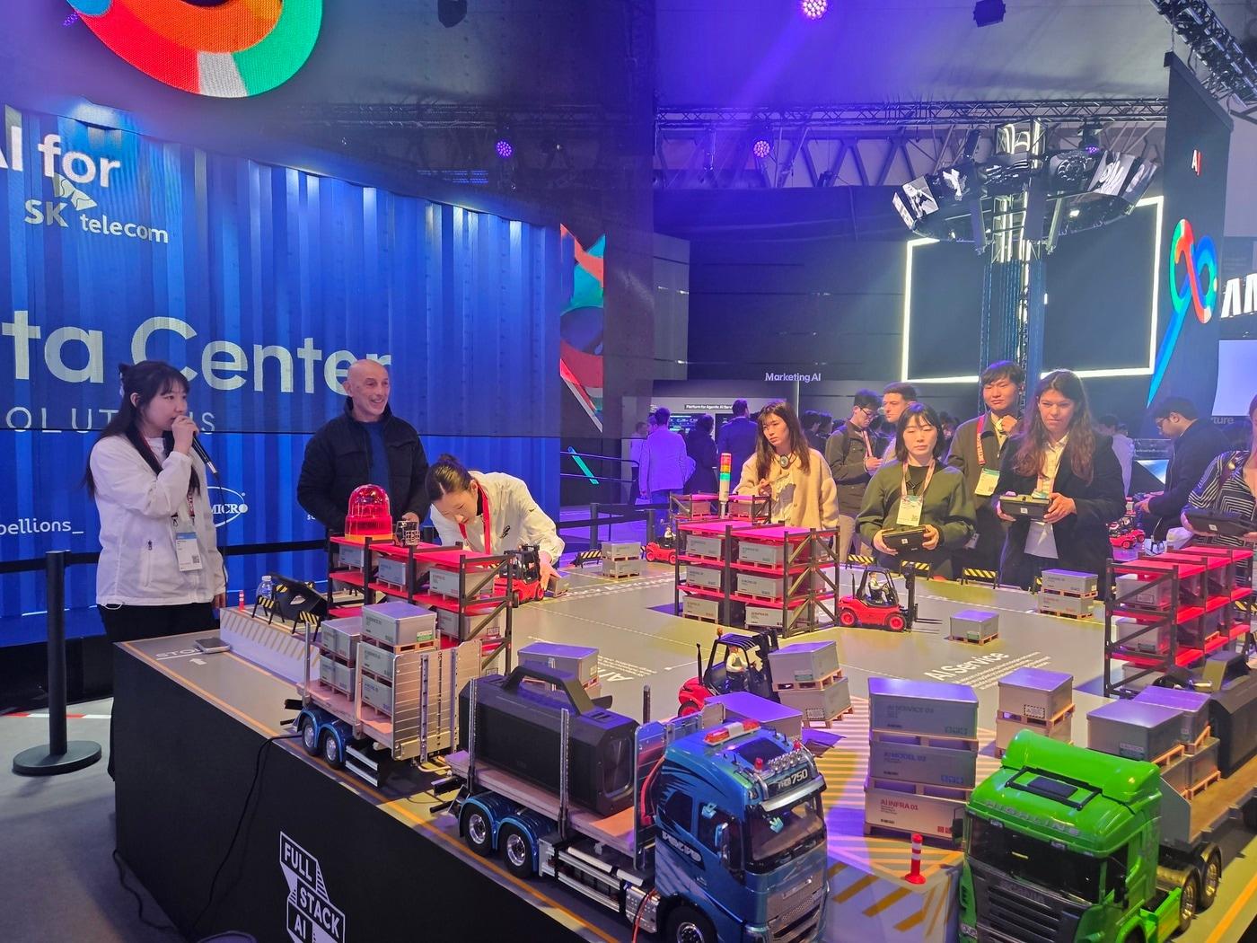 본문 이미지 - 3일(현지시간) MWC26 SK텔레콤 전시관에서 관람객들이 풀스택 AI 개념을 쉽게 이해할 수 있는 '지게차 이벤트'에 참여하고 있다.