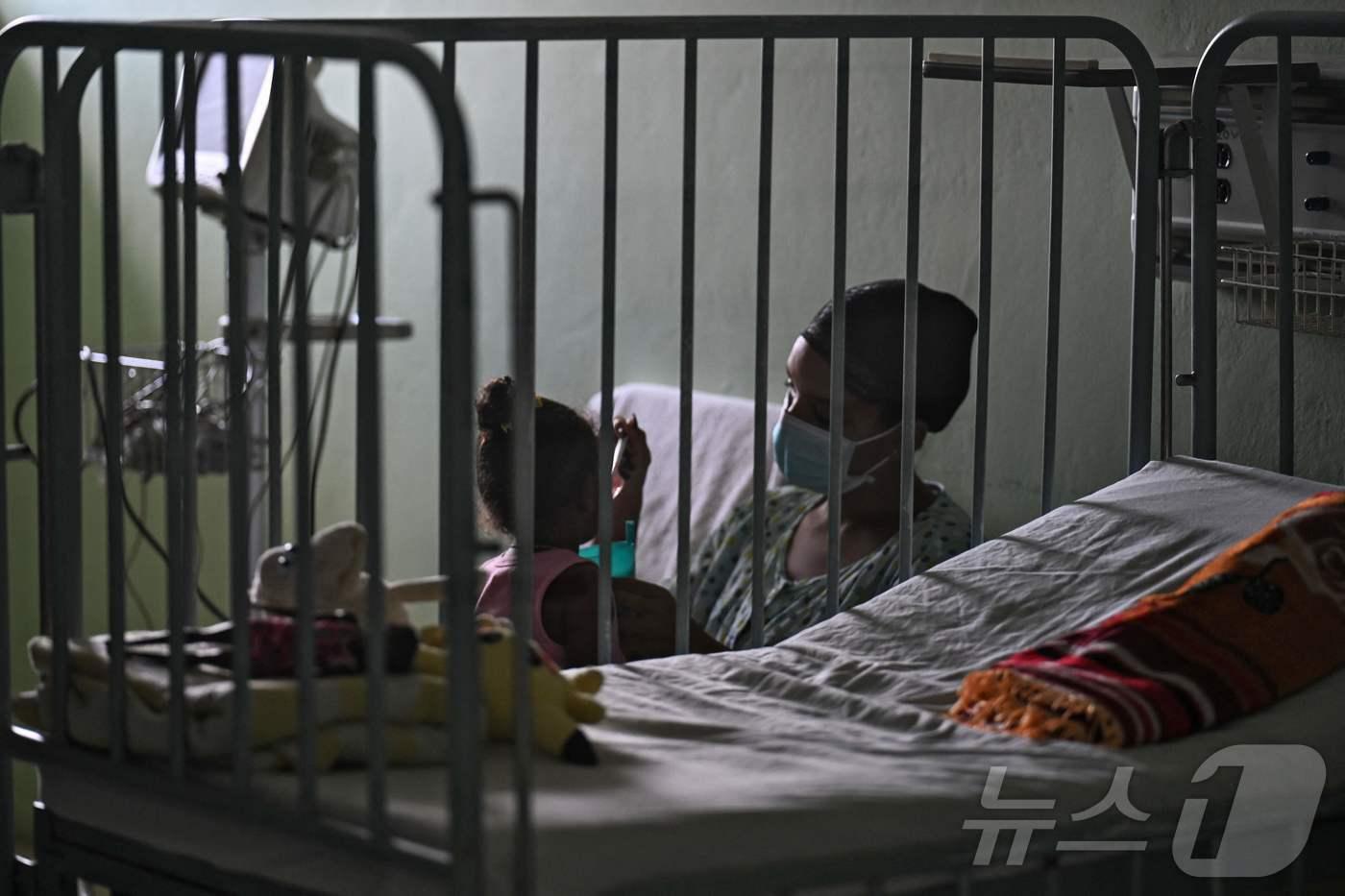 본문 이미지 - 한 여성이 26일(현지시간) 멕시코의 누에스트라아메리카 선단이 가져온 인도적 지원의 수혜를 받은 쿠바 하바나 윌리엄 솔레르 소아 심장병 센터에서 딸을 돌보고 있다. 2026.3.26 ⓒ AFP=뉴스1