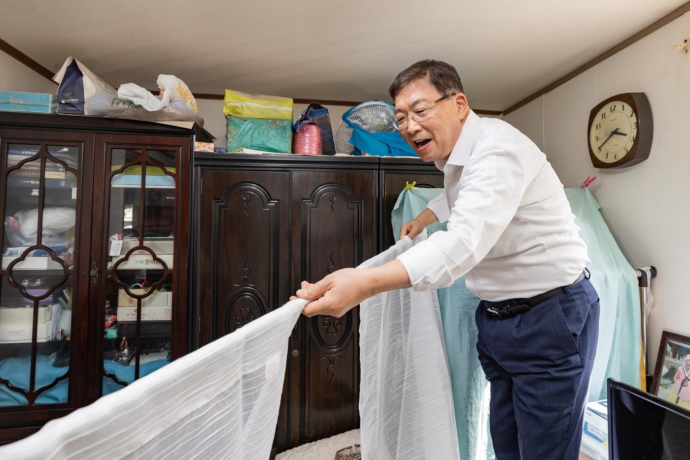 본문 이미지 - 어르신 댁을 찾아가 커튼을 달아주고 있는 김경호 광진구청장