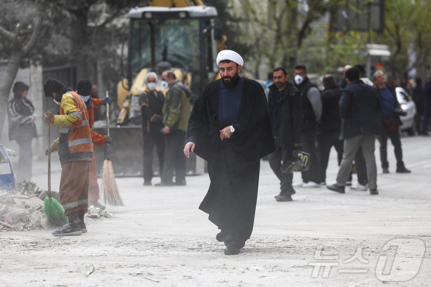 본문 이미지 - 29일(현지시간) 이란 테헤란에서 한 성직자가 공습으로 피해를 입은 카타르 매체 알아라비 TV 건물 근처를 걷고 있다. 2026.03.29. ⓒ 로이터=뉴스1