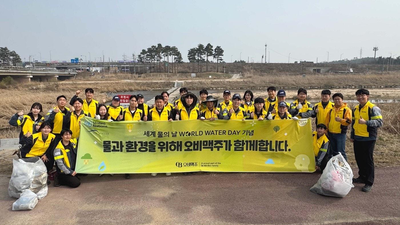 본문 이미지 -  27일 오비맥주 이천공장 임직원들이 이천 복하천 일대에서 환경 정화 활동을 마치고 기념사진을 찍고 있다.(오비맥주 제공)