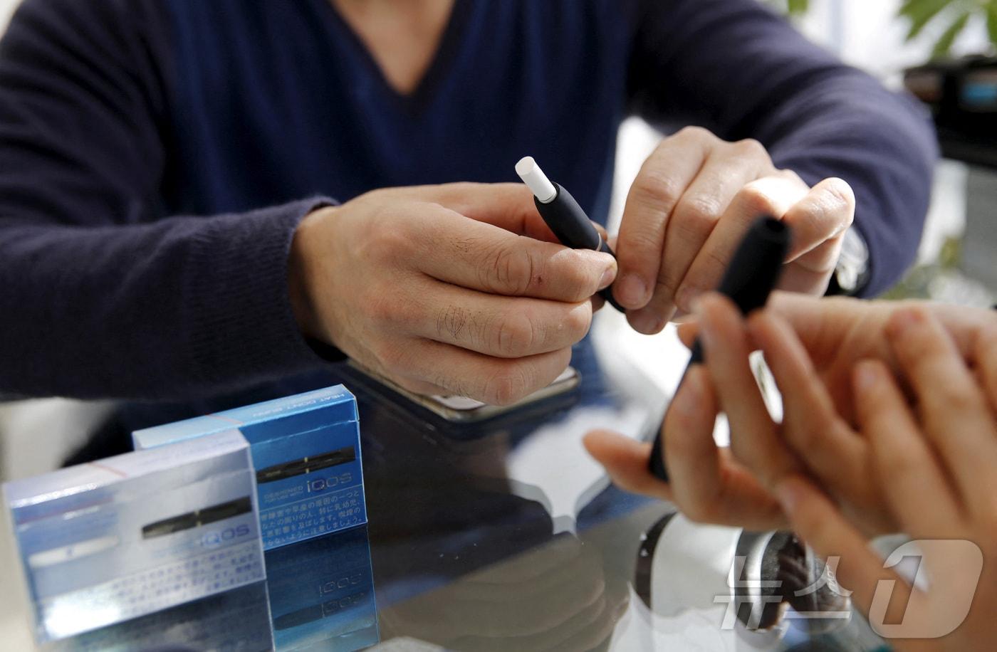 본문 이미지 - 일본에서 4월부터 담뱃세, 법인세, 소득세 등 3개 세목에서 방위비 증액을 위한 증세를 시작한다. 한 고객이 일본 도쿄에 위치한 아이코스(iQOS) 매장에서 제품을 사용해 보고 있다. 2016.03.03. ⓒ 로이터=뉴스1