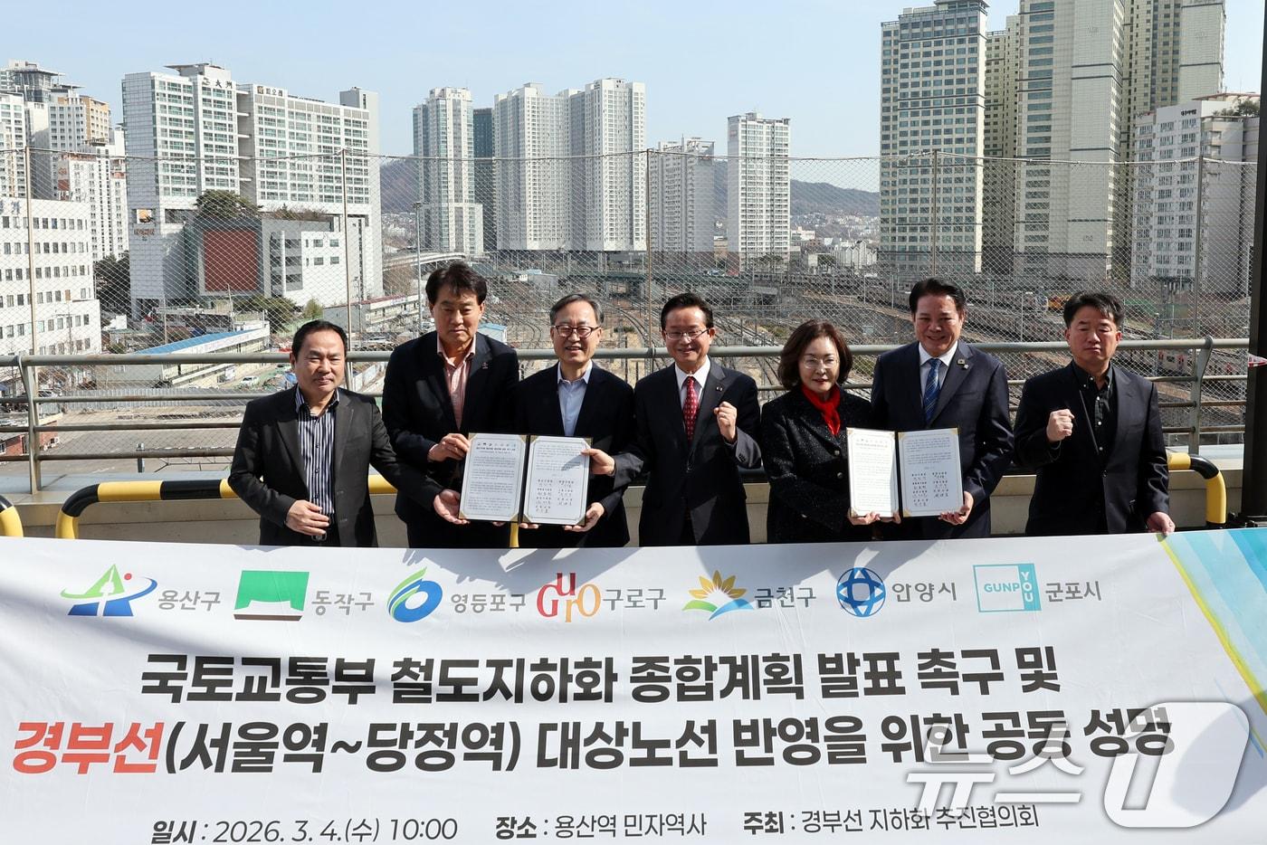 본문 이미지 - 박희영 용산구청장을 비롯한 경부선 지하화 추진협의회가 4일 오전 서울 용산역에서 열린 '국토교통부 철도지하화 종합계획 발표 촉구 및 경부선(서울역~당정역) 대상노선 방영을 위한 공동 성명식'에서 기념촬영을 하고 있다. 협의회에는 서울 용산구·동작구·영등포구·구로구·금천구와 경기 안양시·군포시 등 7개 기초지자체가 참여하고 있다. 2026.3.4 ⓒ 뉴스1 황기선 기자