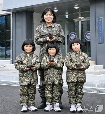 본문 이미지 - 해군 제8전투훈련단 소속 이은주 상사와 세쌍둥이 딸(왼쪽부터 장은진(첫째), 장소진(셋째), 장유진(둘째) 양, 5세)들이 지난달 26일 8전단 예하 예비전력관리전대 건물 앞에서 소아암 아동 돕기를 위해 자른 각 25cm 길이의 머리카락을 손에 들고 기념사진을 촬영하고 있다.(해군 제공)