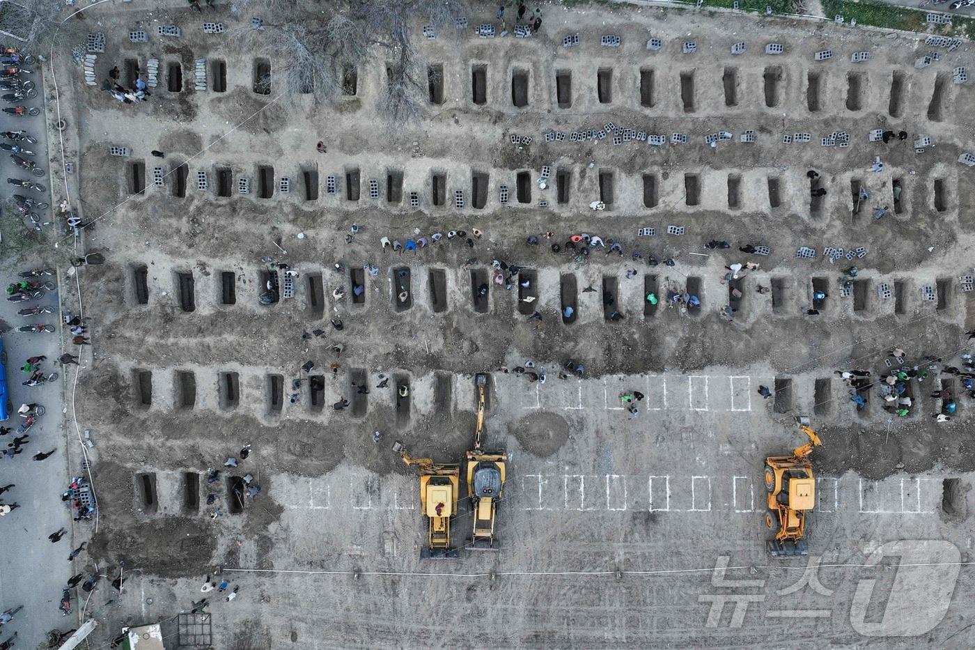 본문 이미지 - 미국과 이스라엘의 공습 첫날인 지난달 28일(현지시간) 이란 남부 호르모즈간주의 한 여자 초등학교가 공격을 받아 수업 중이던 여학생 다수를 포함해 최대 181명이 사망한 것으로 전해졌다. 지난 3일 이들의 장례식이 진행된 가운데 굴착기를 이용해 아이들이 묻힐 땅을 파는 작업이 진행되고 있다.(이란 프레스센터 배포) ⓒ AFP=뉴스1