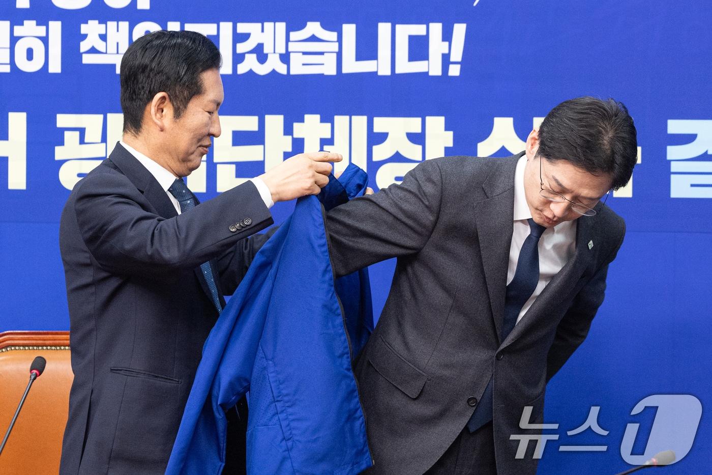 본문 이미지 - 지난 5일 서울 여의도 국회에서 열린 더불어민주당 공천 심사 결과 발표에서 정청래 대표가 경남지사 후보로 단수 공천된 김경수 지방시대위원장에게 점퍼를 입혀주고 있다. 2026.3.5 ⓒ 뉴스1 이승배 기자
