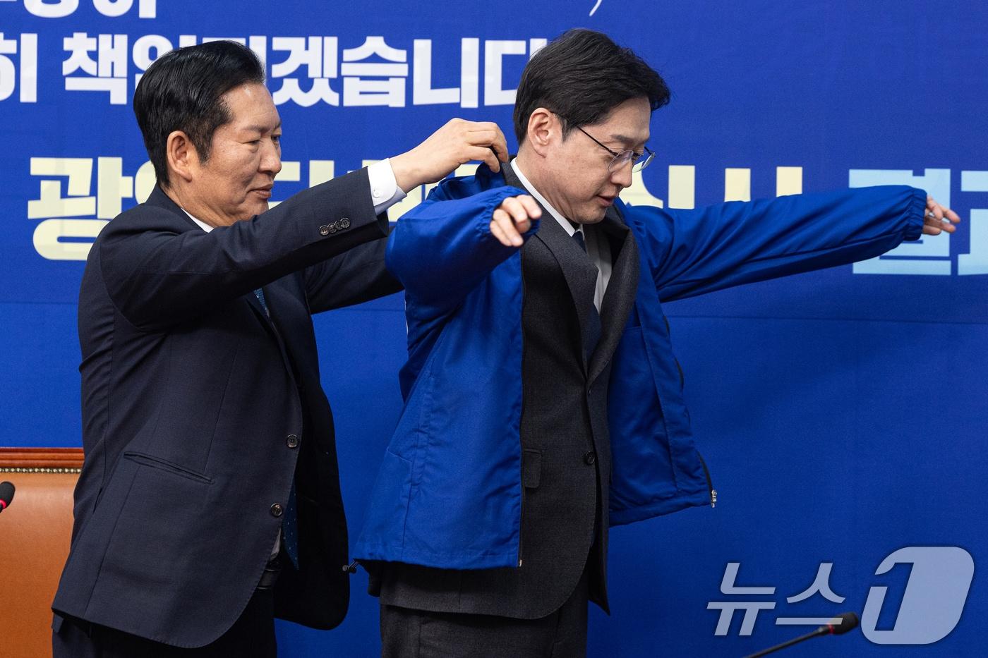 본문 이미지 - 5일 서울 여의도 국회에서 열린 더불어민주당 공천 심사 결과 발표에서 정청래 대표가 김경수 지방시대위원장에게 점퍼를 입혀주고 있다. 더불어민주당은 6·3 지방선거 '3호 단수공천'으로 김경수 대통령 직속 지방시대위원회 위원장을 선정했다. 2026.3.5 ⓒ 뉴스1 이승배 기자