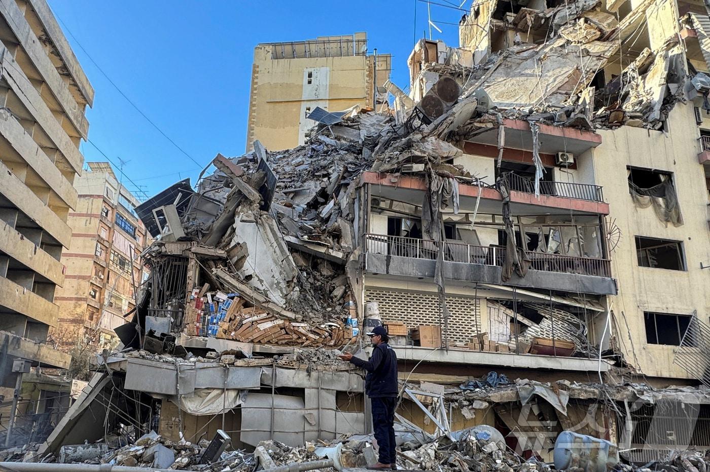 본문 이미지 - 미·이스라엘과 이란의 분쟁 속에서 헤즈볼라와 이스라엘 간의 충돌이 재개된 가운데, 5일(현지시간) 레바논 베이루트 남부 교외에 대한 이스라엘의 공습 후 파손된 건물 옆에 한 남성이 서 있다. 2026.03.05 ⓒ 로이터=뉴스1