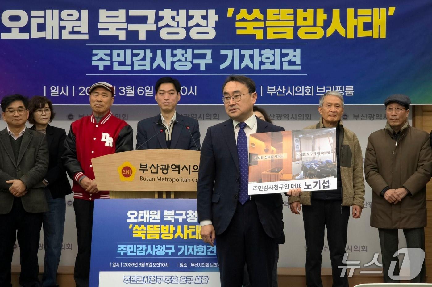 본문 이미지 - 노기섭 '주민감사청구인' 대표가 윤석열 전 대통령의 대통령 집무실 사우나 설치 사진과 오태원 구청장의 쑥뜸방 사진이 담긴 패널을 들고 나와 두 사건의 공통점 대해 설명하고 있다.2026.03.06/뉴스1 ⓒ News1 이주현 기자