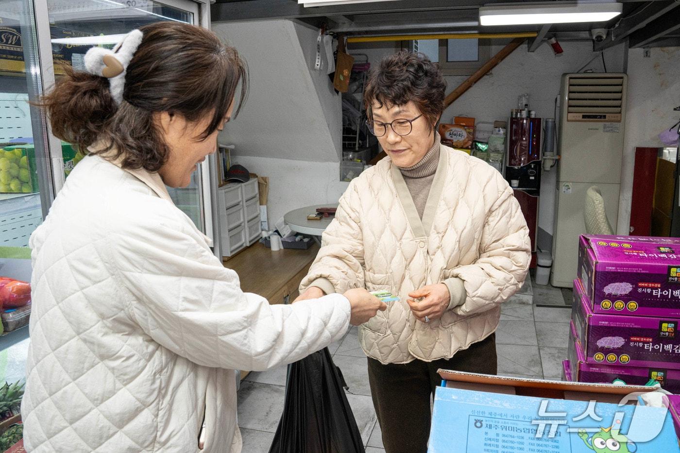 본문 이미지 - 농어촌 기본 소득이 지급된 지난달 27일 남해군 남해읍의 한 과일가게에서 권현선 씨(53·여)가 기본 소득 카드로 과일을 사고 있다. 2026.2.27/뉴스1 한송학기자