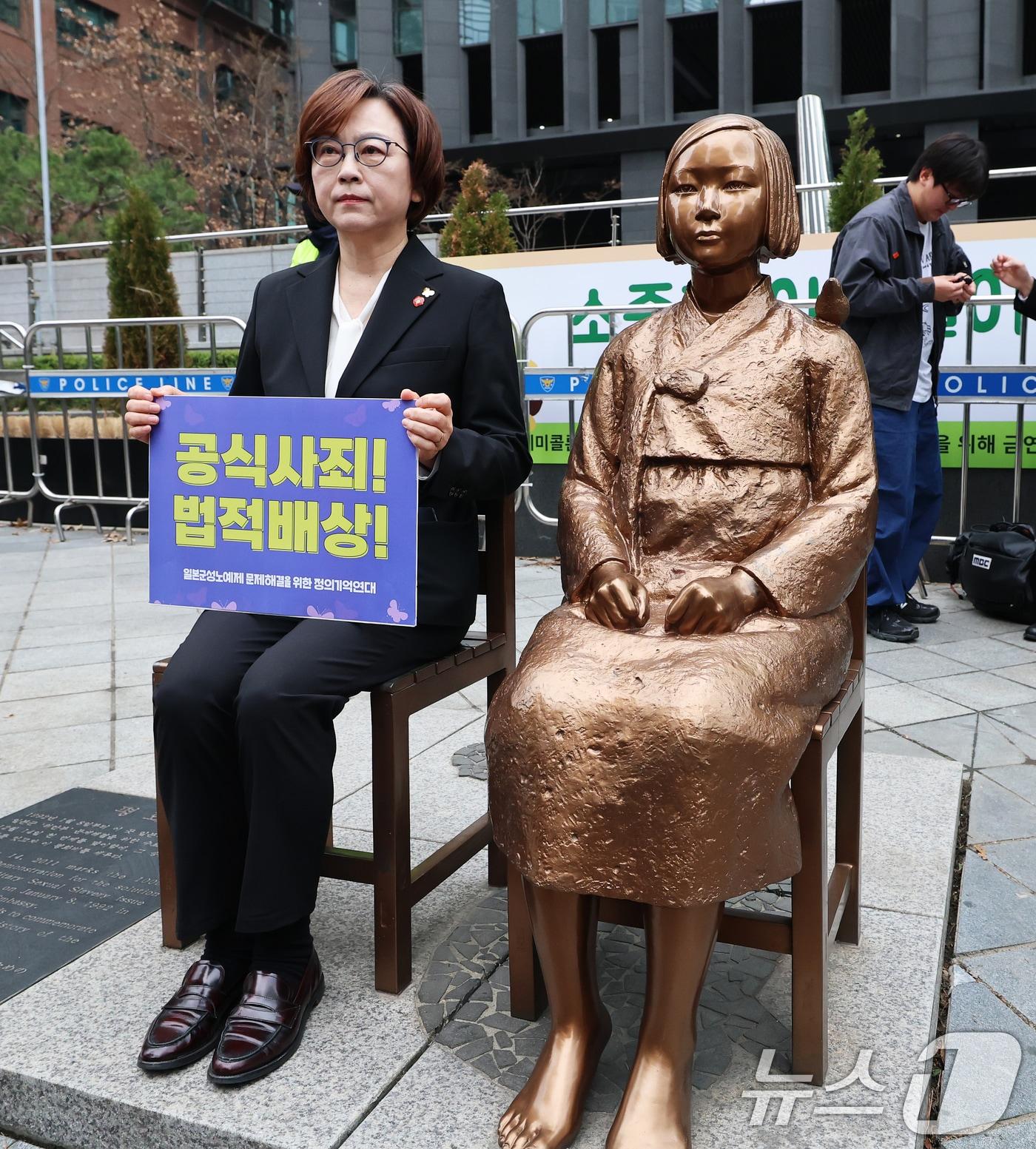 본문 이미지 - 이나영 정의기억연대 이사장이 1일 서울 종로구 옛 주한 일본대사관 앞에서 제1746차 일본군 성노예제 문제해결을 위한 정기 수요시위에 앞서 바리케이드가 철거된 소녀상 곁에 앉아 있다. 2026.4.1 ⓒ 뉴스1 오대일 기자