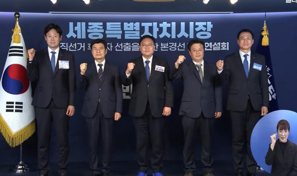 본문 이미지 - 1일 서울 영등포구 여의도 더불어민주당 당사에서 열린 세종시장 공직선거 후보자 선출을 위한 본경선 합동연설회에서 예비후보들이 기념 촬영하고 있다. 왼쪽부터 고준일, 이춘희, 조상호, 홍순식, 김수현 예비후보. / 민주델리 유튜브 캡처