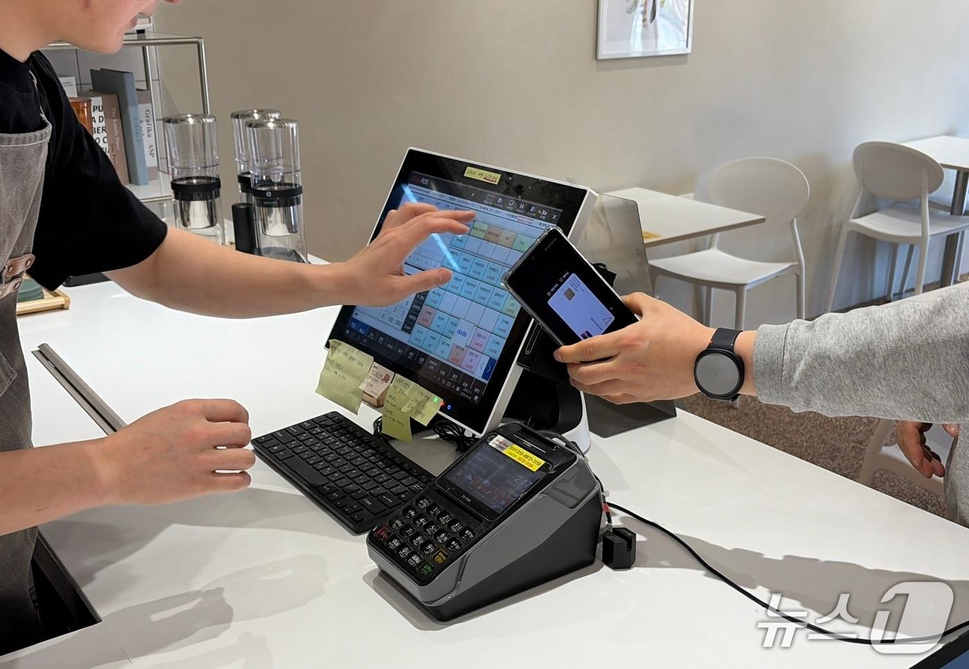 본문 이미지 - 대구 달성군이 연 매출 1억 원 이하 소상공인에게 카드 수수료를 지원한다. 사진은 한 고객이 카페에서 음료를 주문하며 카드로 비용을 치르고 있는 장면.(대구 달성군 제공. 재판매 및 DB금지)