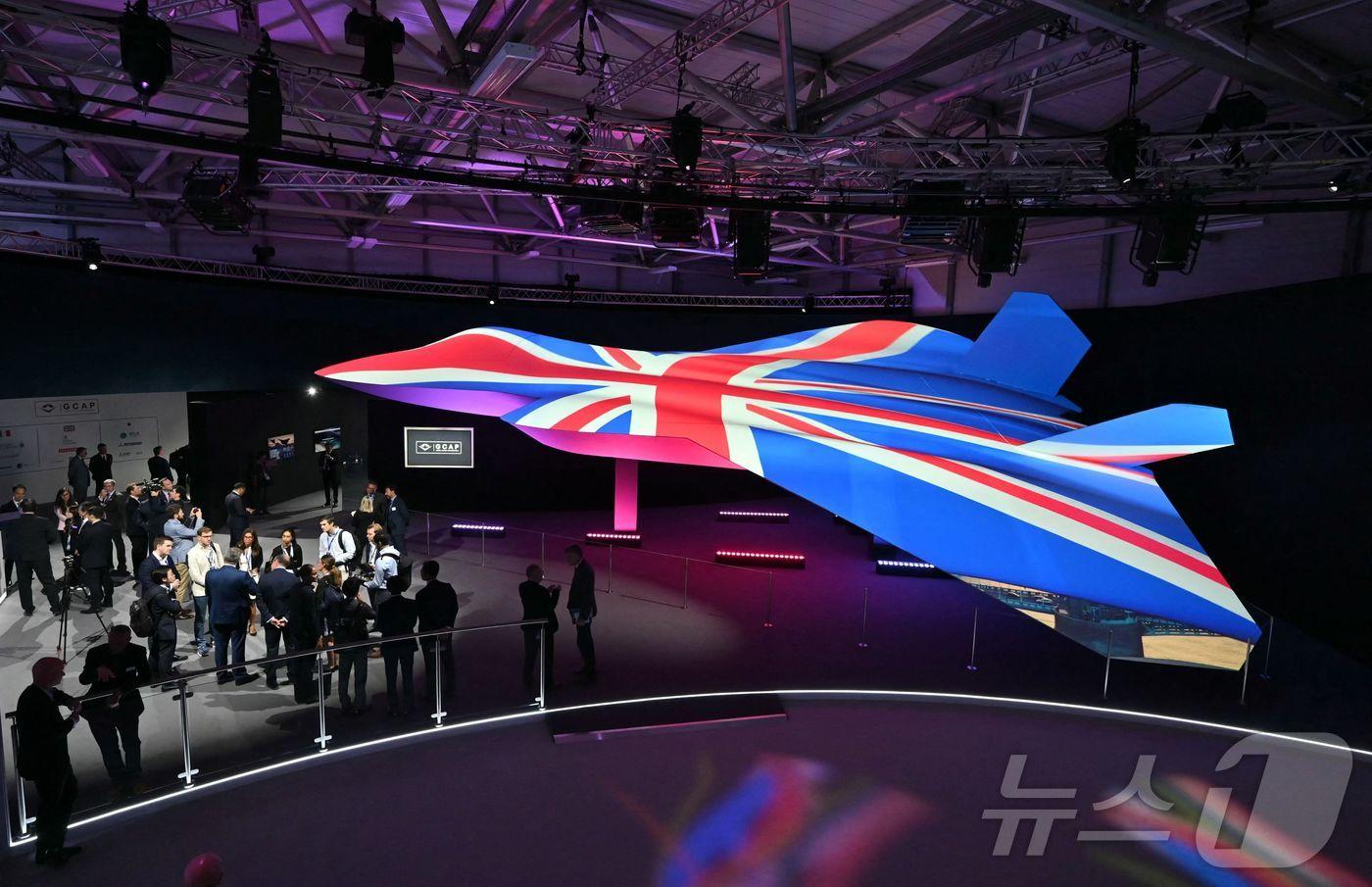 본문 이미지 - 2024년 7월 22일 영국 판버러 국제에어쇼에서 영국 국기 색깔로 물든 차세대 초음속 전투기 GCAP 콘셉트 디자인을 관계자들이 살펴보고 있다. 2024.07.22. ⓒ AFP=뉴스1