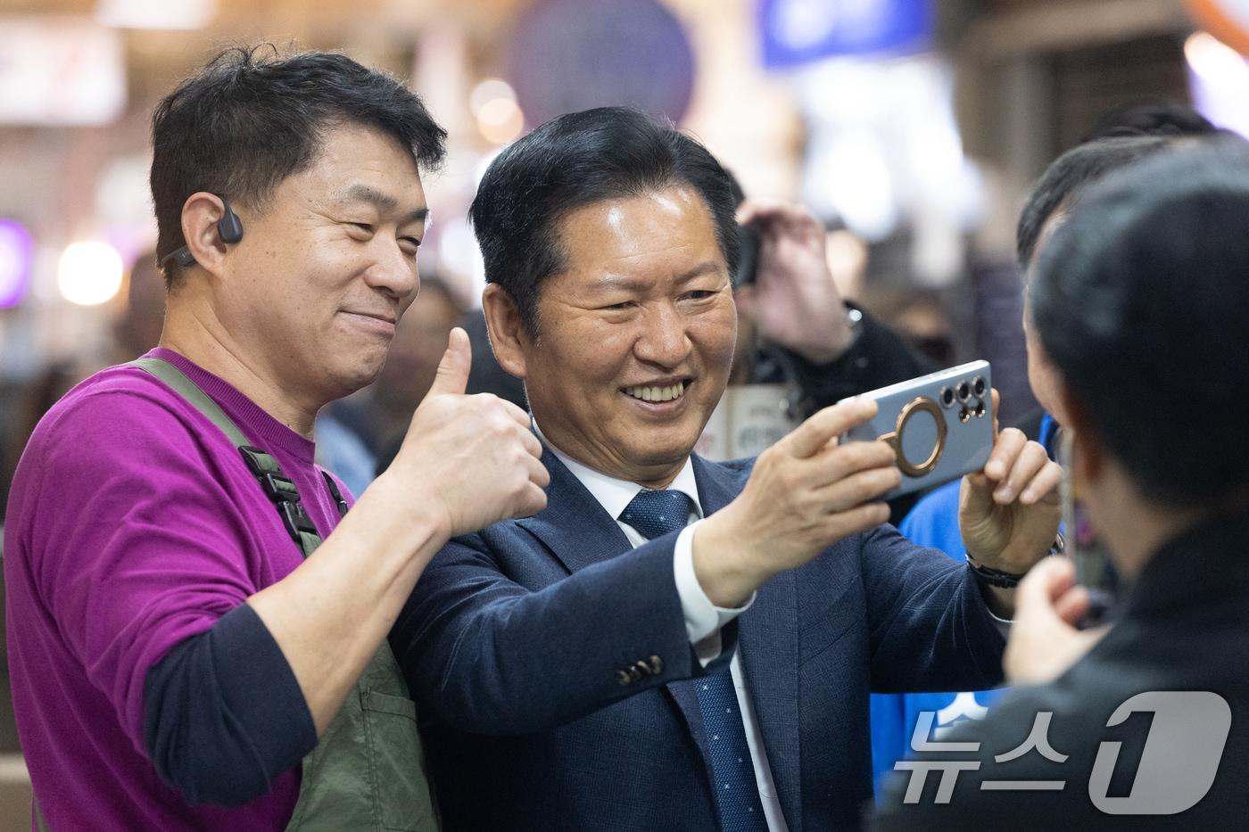 본문 이미지 - 정청래 더불어민주당 대표가 12일 강원 속초관광수산시장을 찾아 상인과 셀카를 찍고 있다. 2026.4.12 ⓒ 뉴스1 이승배 기자
