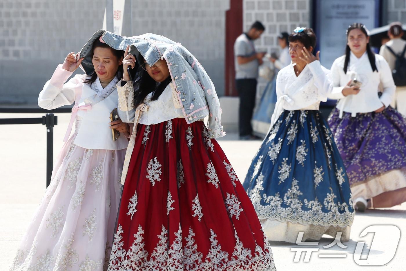 본문 이미지 - 서울 낮 최고 기온이 25도까지 오르는 등 초여름 날씨를 보인 13일 서울 경복궁에서 관광객들이 외투로 햇빛을 가리고 있다. 2026.4.13 ⓒ 뉴스1 김민지 기자