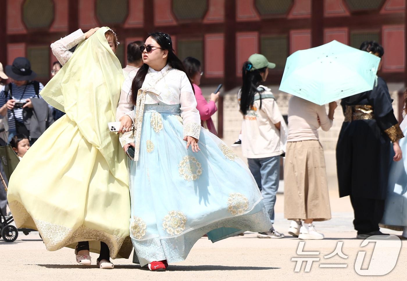 본문 이미지 - 서울 낮 최고 기온이 25도까지 오르는 등 초여름 날씨를 보인 13일 서울 경복궁에서 외국인 관광객이 한복으로 햇빛을 가리고 있다. 2026.4.13 ⓒ 뉴스1 김민지 기자