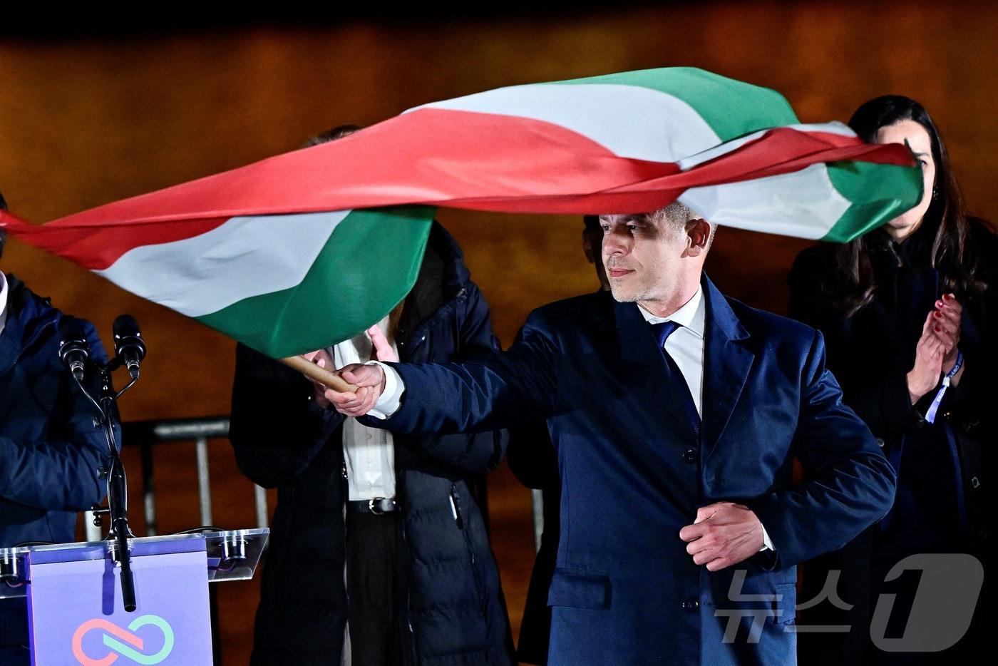 본문 이미지 - 12일(현지시간) 헝가리 총선에서 승리한 페테르 마자르 티사당 대표가 부다페스트에서 국기를 흔들고 있다. 2026.4.13. ⓒ 뉴스1 ⓒ 로이터=뉴스1