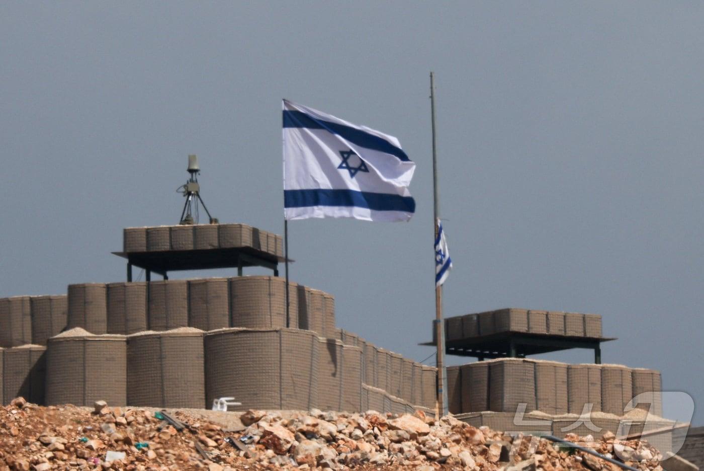 본문 이미지 - 이스라엘과 레바논 국경 인근 군사기지의 이스라엘 국기. 2026.04.13 ⓒ 로이터=뉴스1