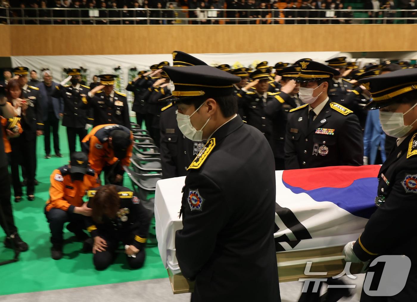 본문 이미지 - 냉동창고 화재를 진화하다 순직한 소방공무원 영결식이 진행된 14일 오전 전남 완도군농어민문화체육센터에서 운구가 진행되는 가운데 한 소방공무원이 무릎 꿇고 오열하고 있다. 2026.4.14 ⓒ 뉴스1 박지현 기자